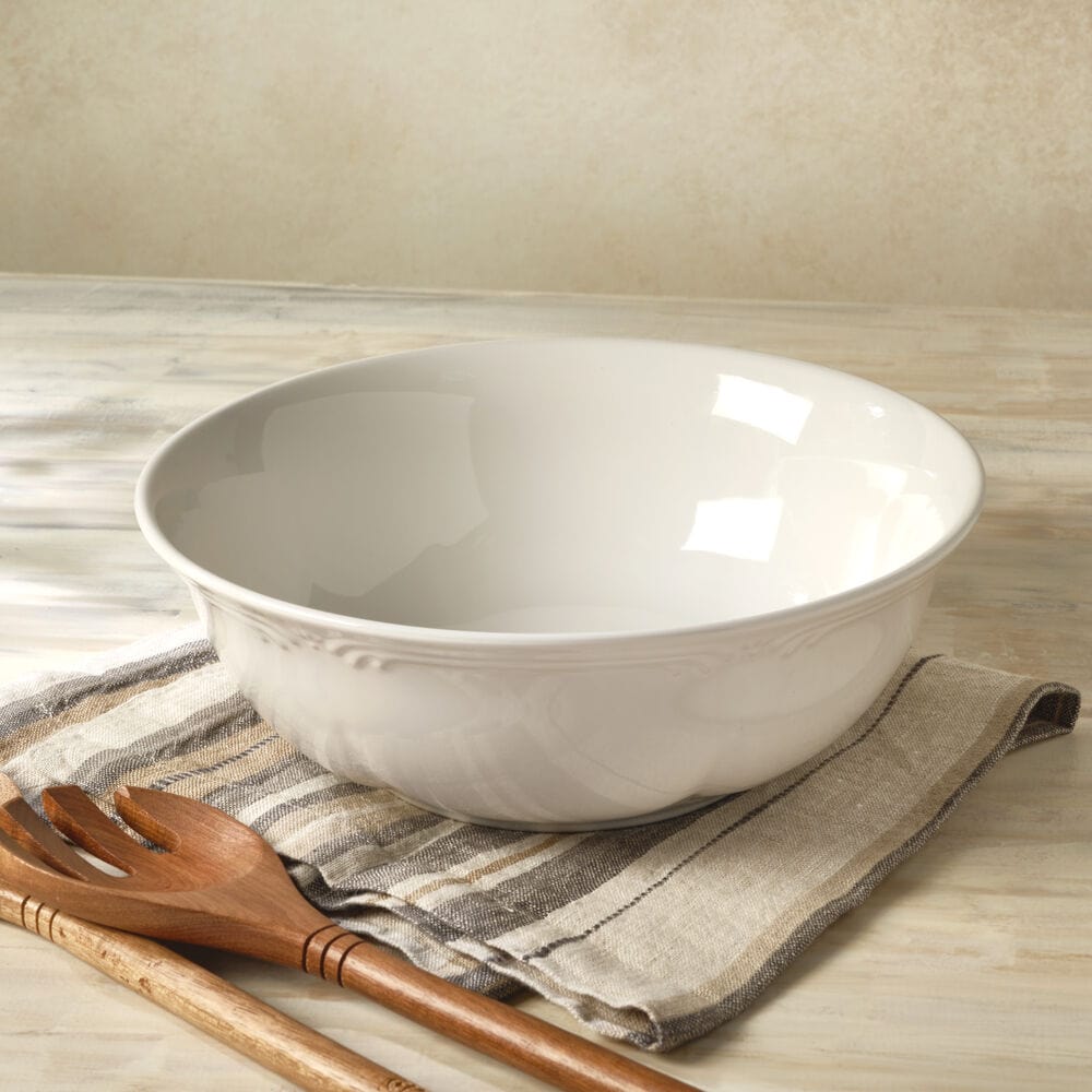 Rustic stoneware pasta serve bowl on a dining table filled with spaghetti