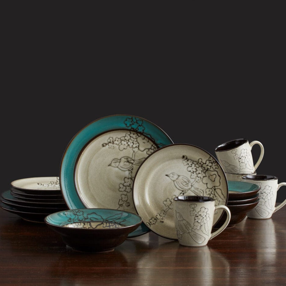 Shot of the entire Song Bird reactive glaze dinnerware set on a rustic table, highlighting the unique patterns