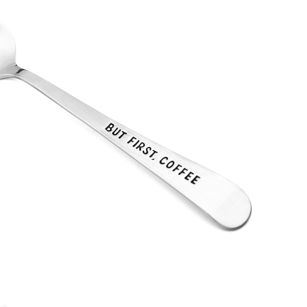 But First Coffee mini spoons in action, stirring a steaming cup of coffee.