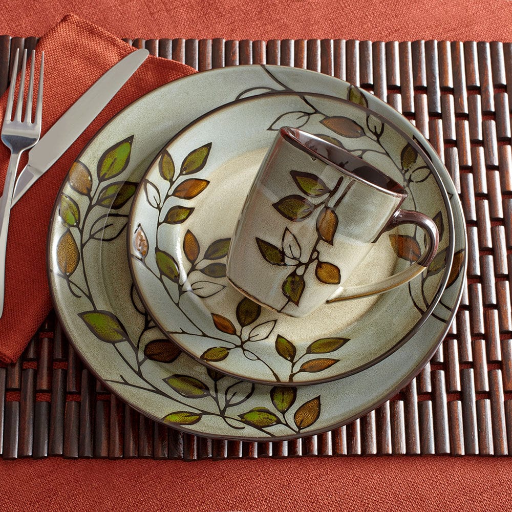 Set of stoneware dishes including dinner plate, salad plate, soup bowl, and mug on a rustic wooden table