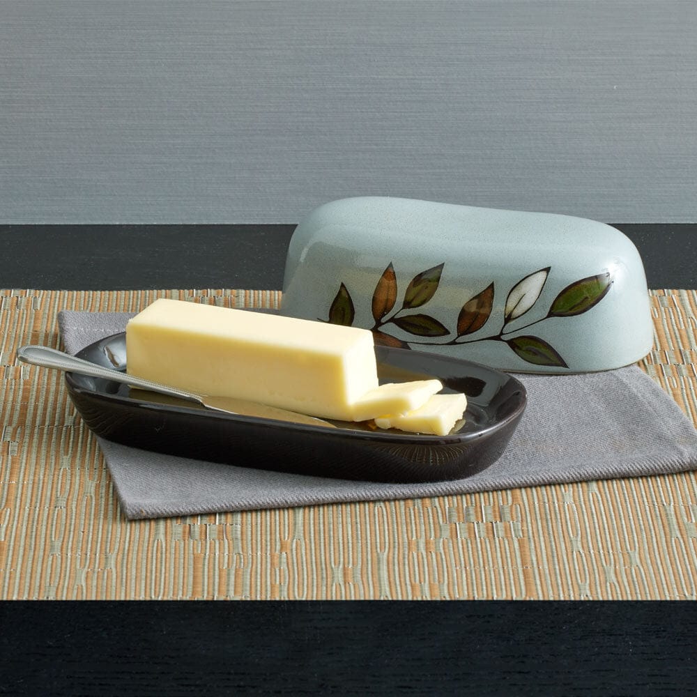 Angled front view of rustic reactive glaze butter dish with lid placed beside base