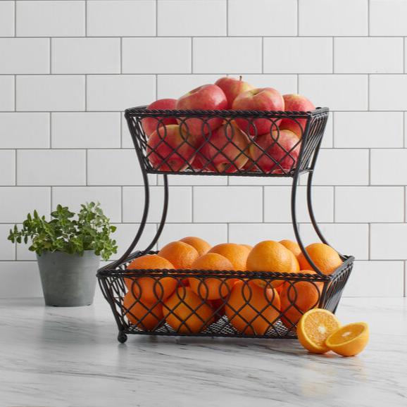 Elegant wrought iron 2-tier kitchen basket showcasing fruits on a countertop.