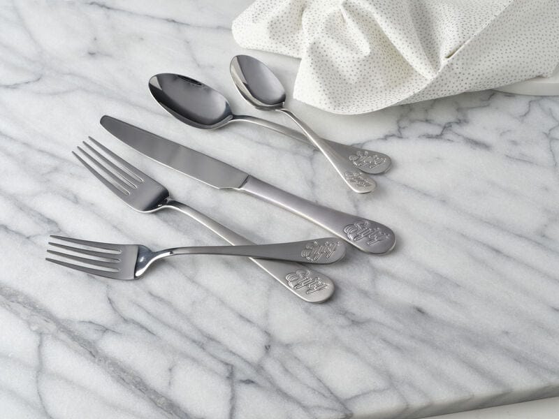 Close-up of whimsical flatware handles with Enjoy inscription on dinner table
