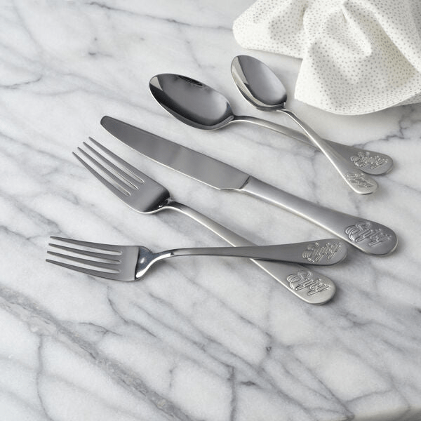 Close-up of whimsical flatware handles with 'Enjoy' inscription on dinner table