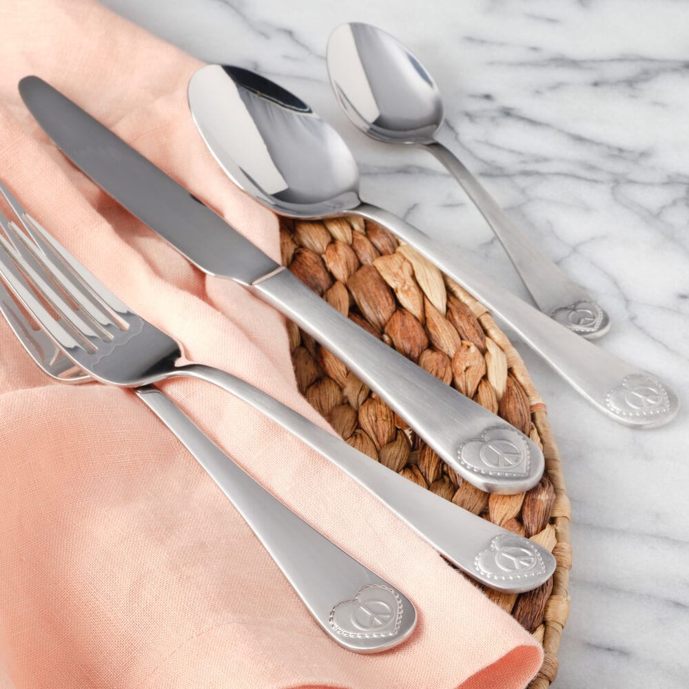 Close-up of stainless steel flatware set with peace sign handles, arranged for a dinner setting
