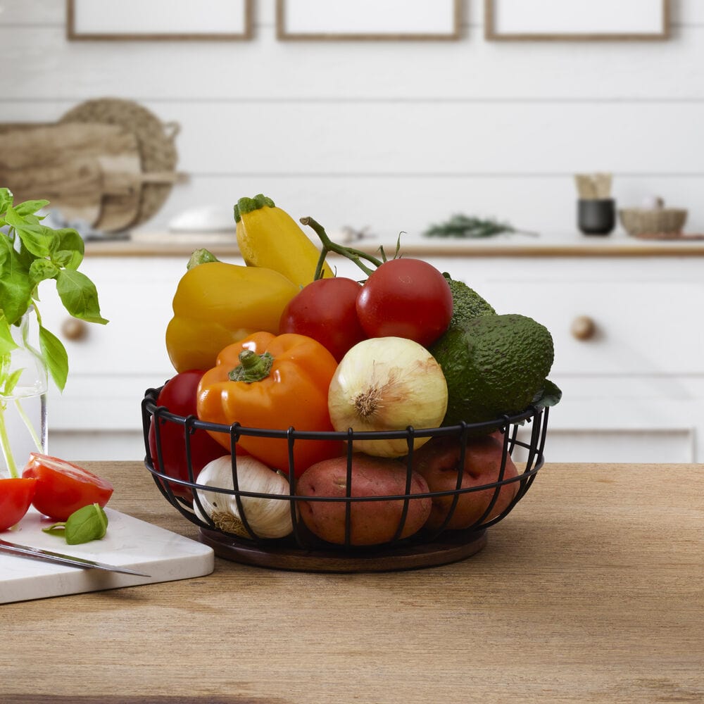Elegant wire cage centerpiece basket showcasing fresh fruits on a dining table.