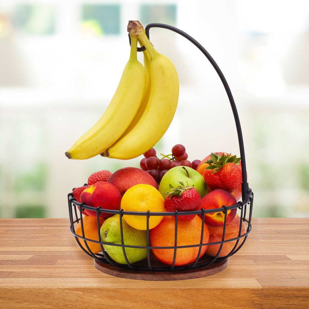 Wire fruit basket with banana hook and wooden base on kitchen countertop