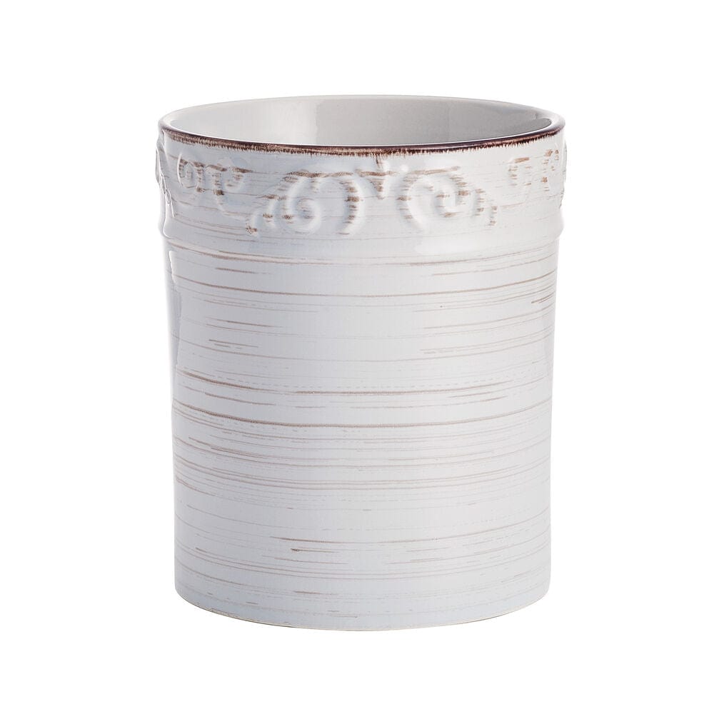White stoneware utensil crock with scroll pattern on kitchen countertop