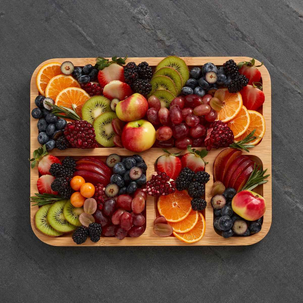 Close-up of compartments filled with cheese, fruits, and nuts on the charcuterie board