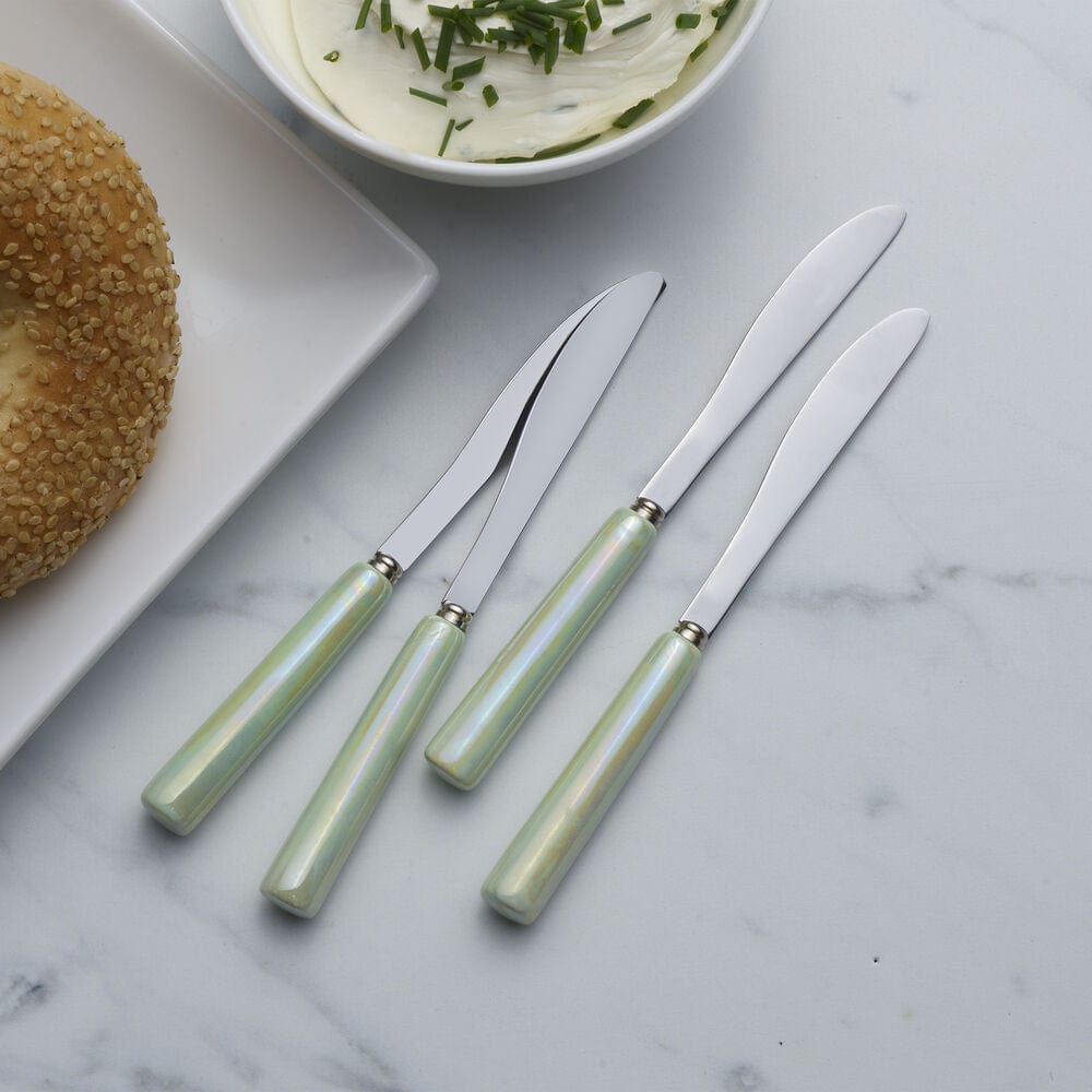 Close-up of ceramic spreaders with green handles on a dining table
