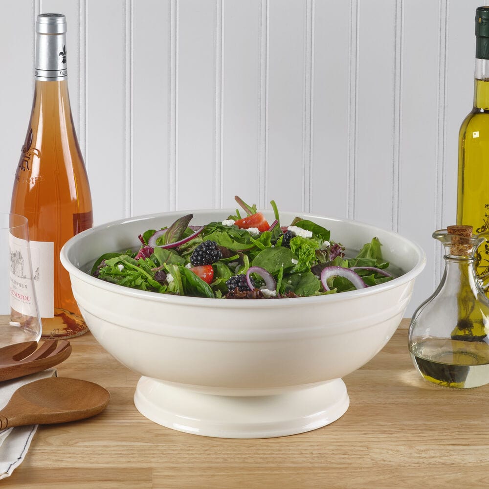 Elegant white footed metal serving bowl showcasing salads at a dinner party.