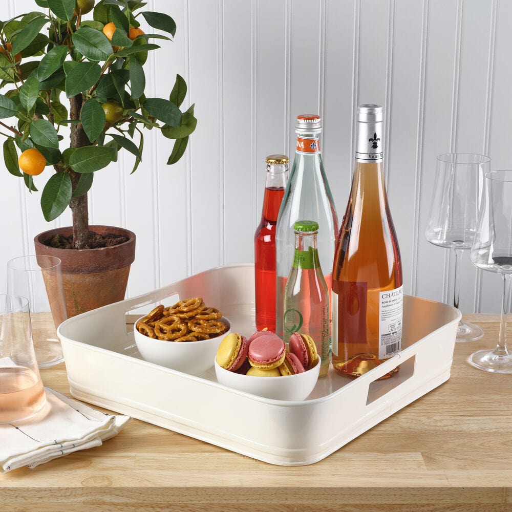 Overhead shot of the white square metal tray styled with appetizers and cocktails