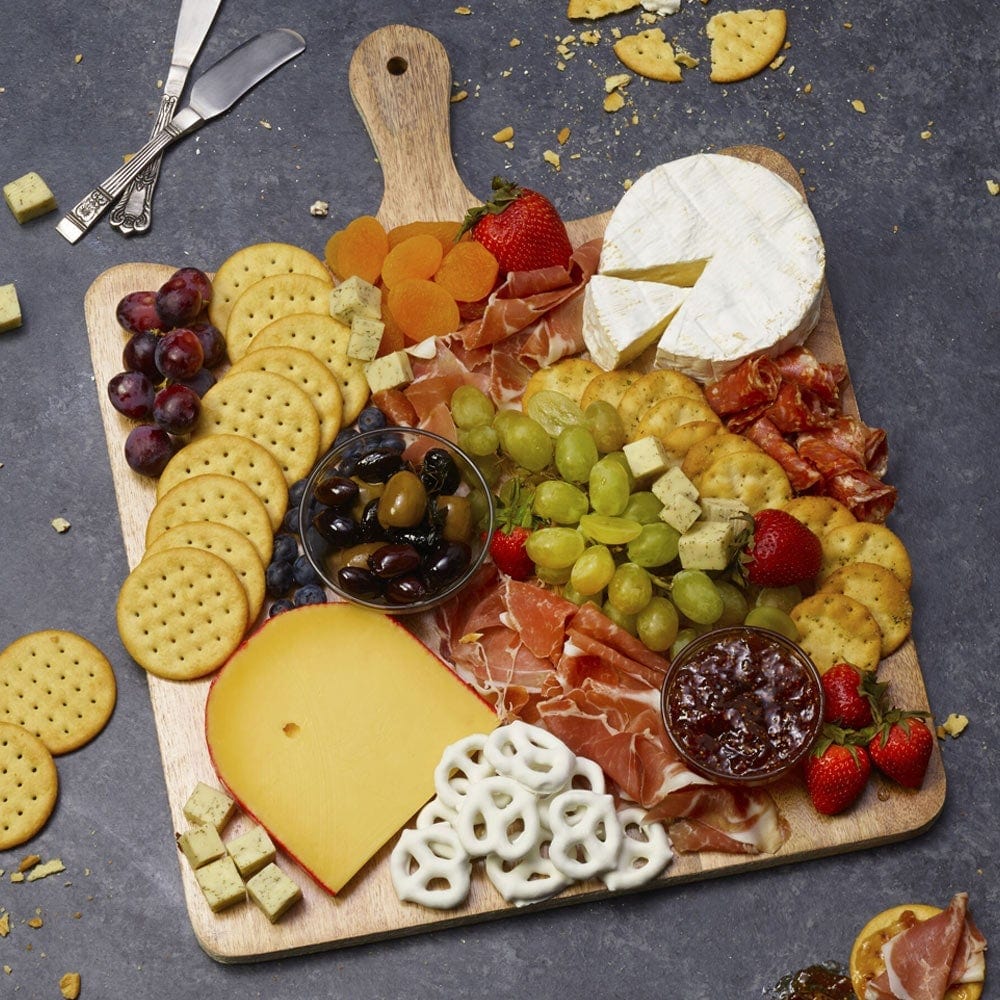 Elegant presentation of mango wood charcuterie board on a dining table.