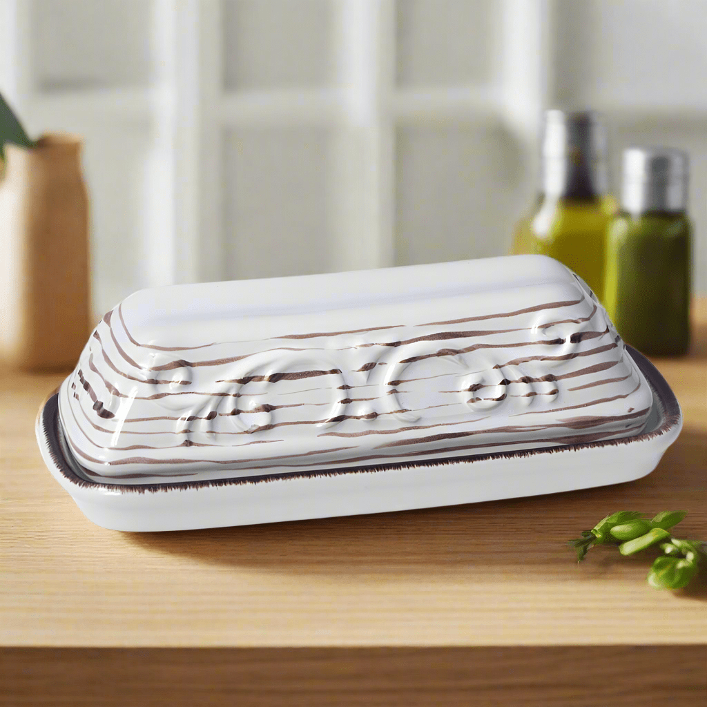 Front view of Trellis white stoneware butter dish with lid on a kitchen counter