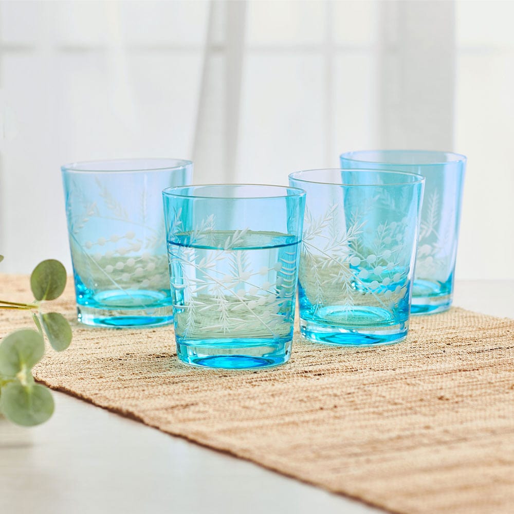 Close-up of hand-cut wildflower design on blue whiskey glass