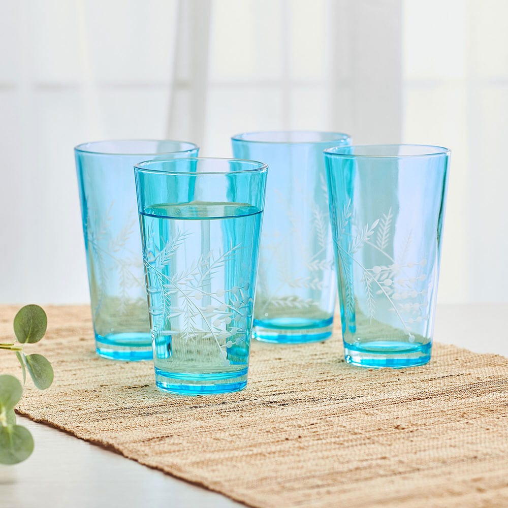 Close-up of whimsical blue highball glasses set against a rustic table setting, ideal for cocktails.