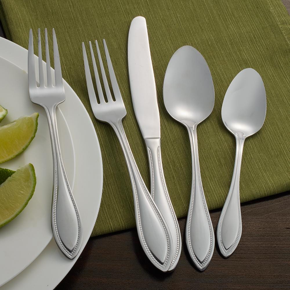 Elegant stainless steel flatware set displayed on a dining table with elegant decor.