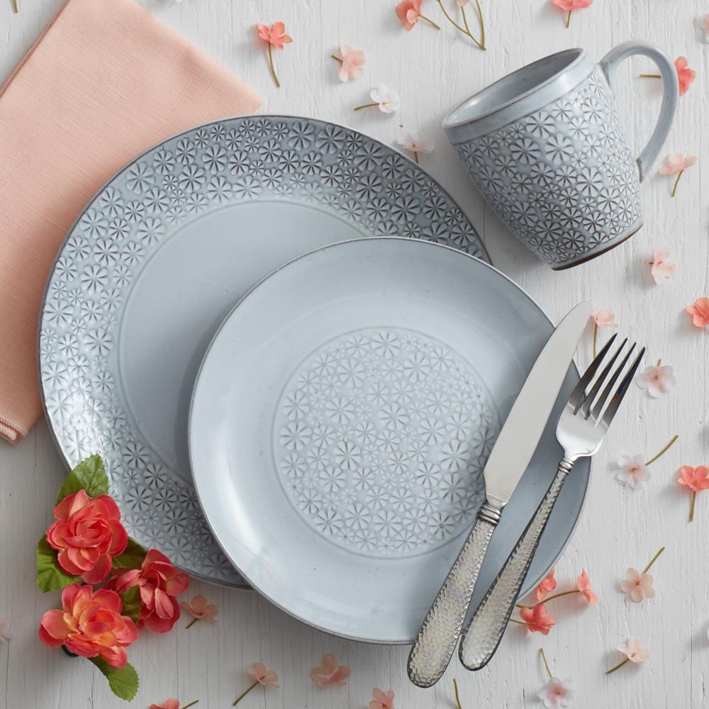 Set of 16 white stoneware dinner plates, bowls, and mugs arranged on a dining table