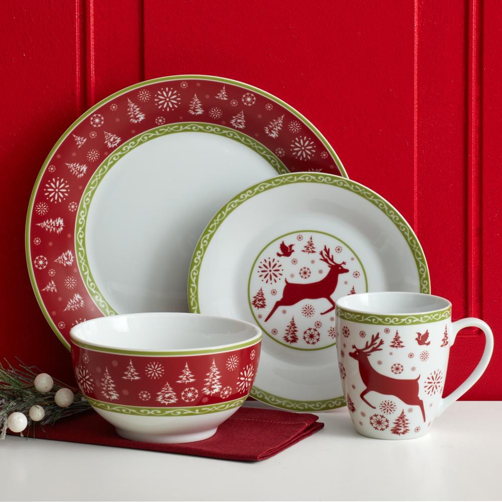 Overhead view of porcelain dinner set with red deer design and green garland border, styled for a Christmas dinner table.