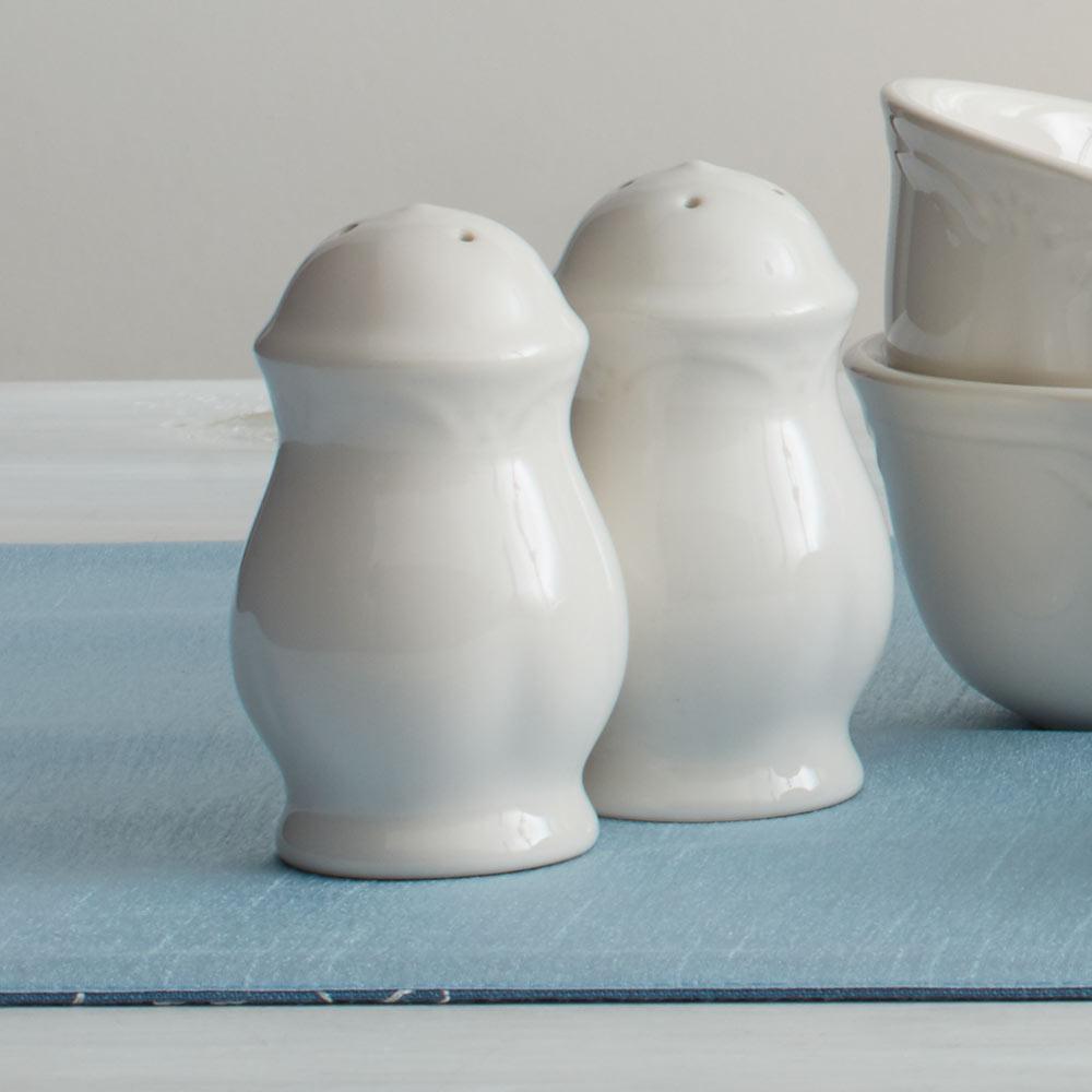 Ornate salt and pepper shakers with embossed design on a dining table setting.