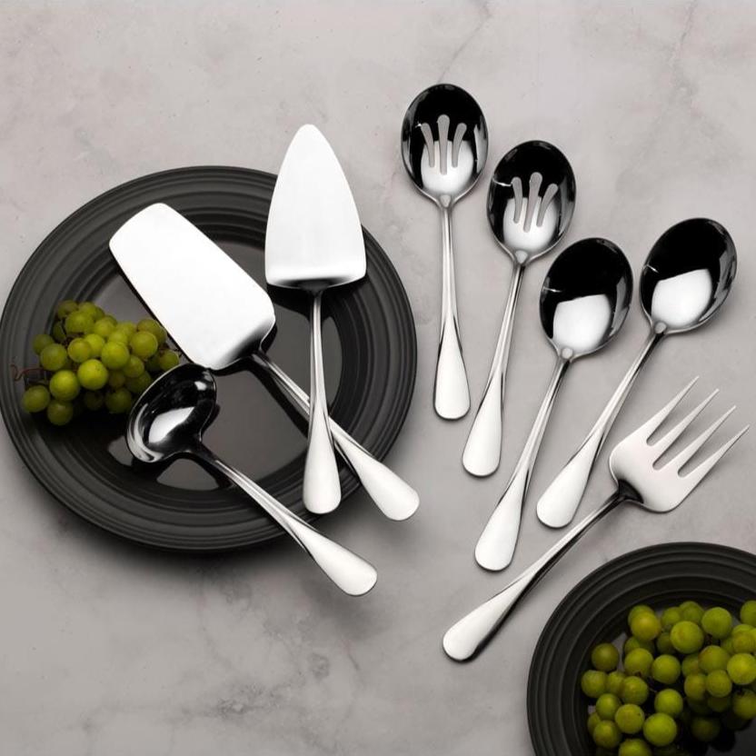 Stainless steel serving set with ladle, cake server, and cold meat fork on a dining table
