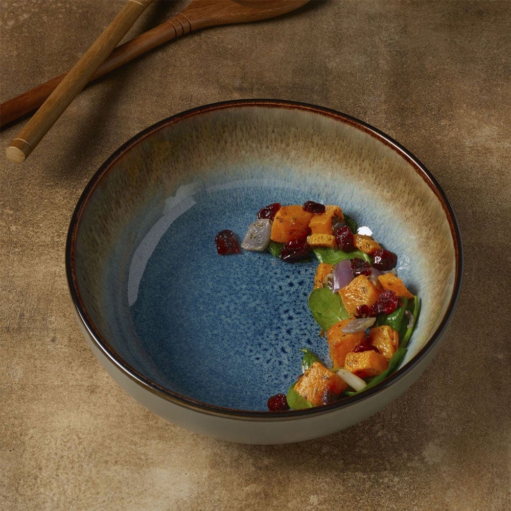 Close-up of the blue stoneware serve bowl's reactive glaze finish showing speckled pattern