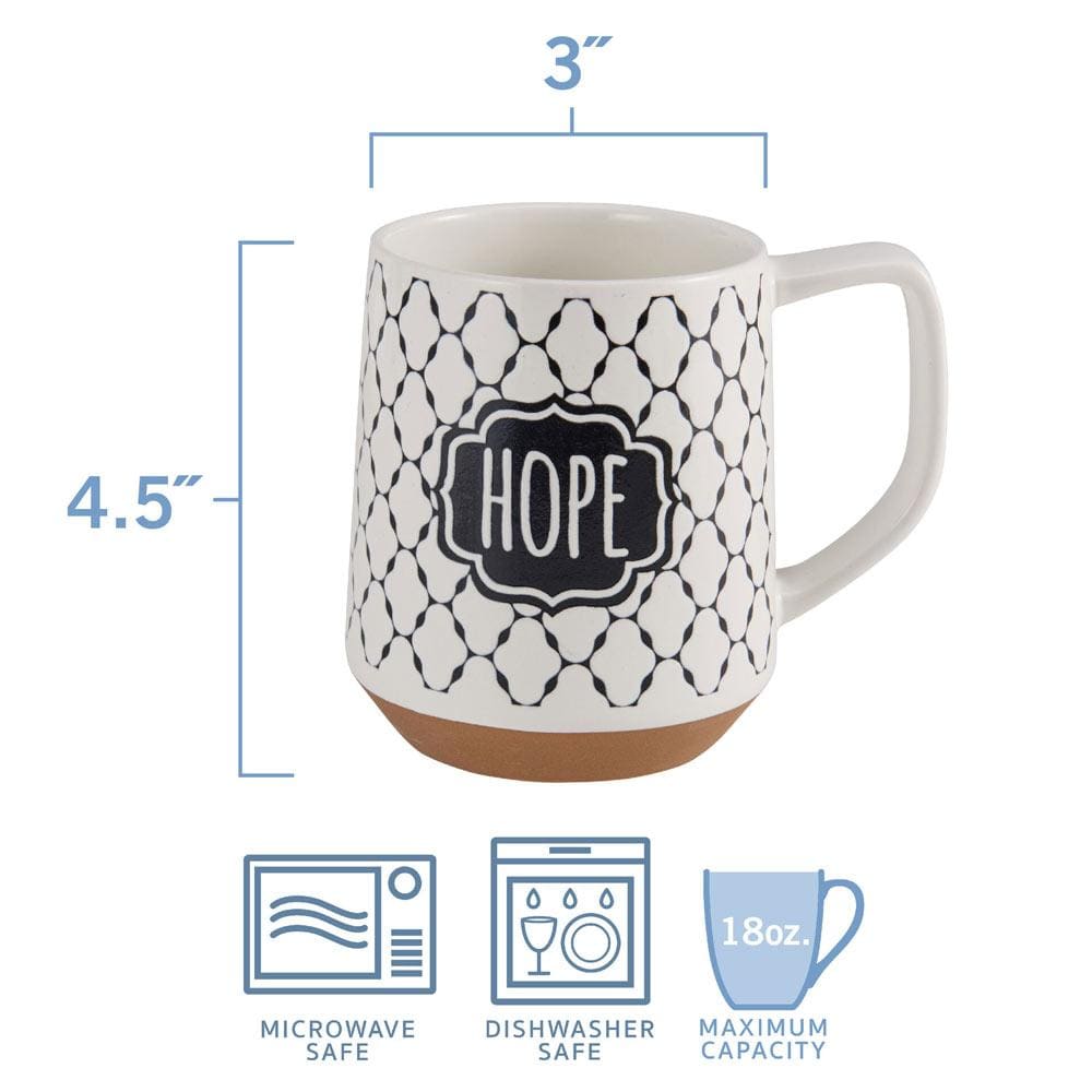 A hand holding a stoneware coffee mug with the word Joy printed, against a cozy morning backdrop.