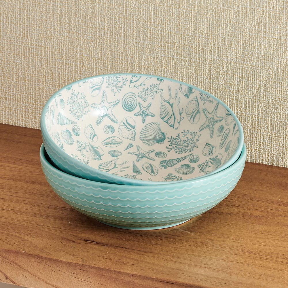 Close-up of beach-themed ceramic pasta bowls with starfish design on a wooden table